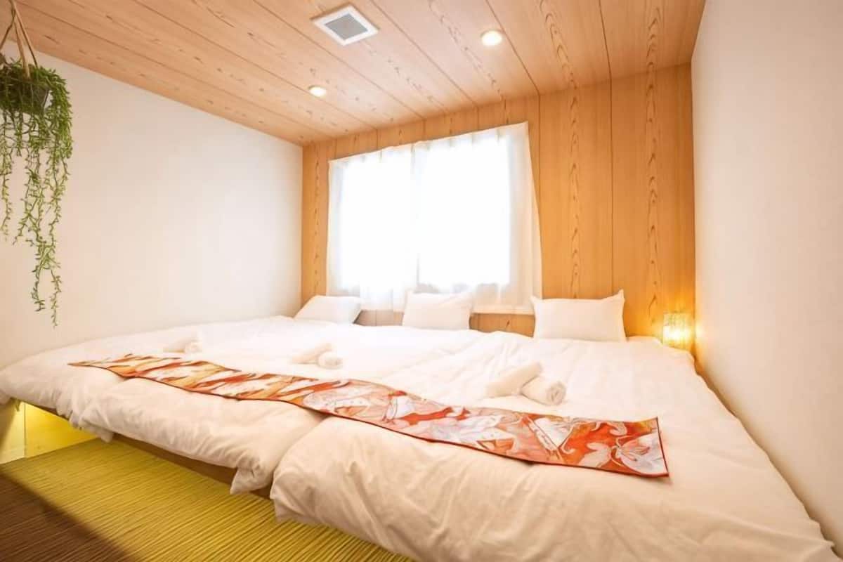 Une chambre avec un grand lit, un plafond en bois et une fenêtre avec des rideaux.