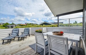 Relax on the elevated deck with a view of the surrounding landscape, featuring a table, chairs, and lounge chairs.