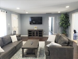 Relax in this stylish living room with a large flat-screen TV, comfortable sofas, and a potted plant.