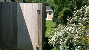 A wooden fence with a gate, a grassy yard, and a house in the background. - Newly built house, Central A/C, Walk to ferry, beach, and town (Tisbury)