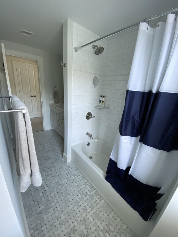 A bathroom with a bathtub, a shower curtain, a towel rack, a mirror, and a toilet. - Newly built house, Central A/C, Walk to ferry, beach, and town (Tisbury)