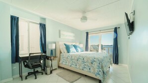 Une chambre à coucher avec un lit, un bureau, une chaise et une vue sur la mer.