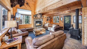 L’intérieur d’un chalet confortable, avec une cheminée, des canapés en cuir et une tête de bison fixée au mur.