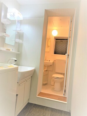 A compact bathroom with a white sink, mirror, and toilet. - Tokyo Kakan (Tokyo)