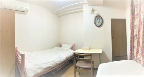 A small, single-room accommodation with a bed, a desk, and a chair.