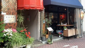 Un restaurante con toldo rojo y fachada de ladrillo.