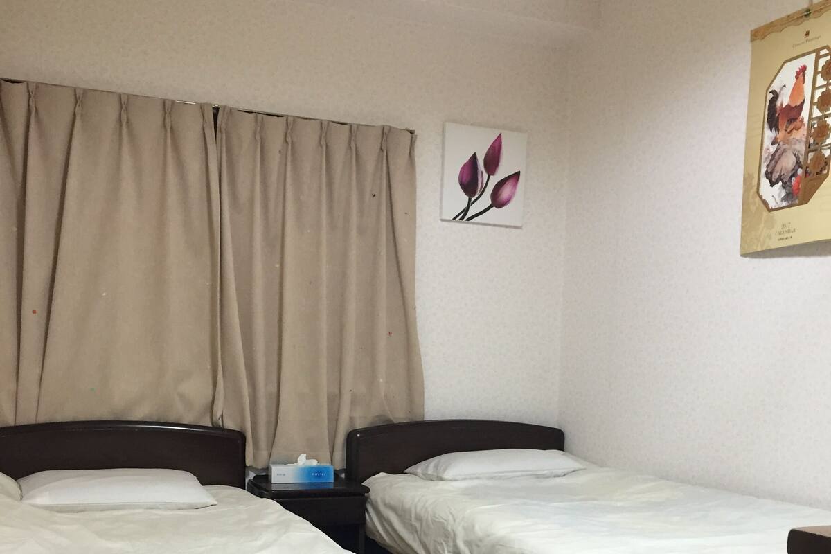 A room with two single beds, a nightstand, a wall clock, and a calendar.