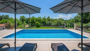 A rectangular swimming pool with two umbrellas and lounge chairs. - Pet friendly home in Labin (Labin)