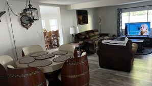 A living room with a dining table, chairs, a sofa, and a television. - Cozy County Home (Richfield Springs)