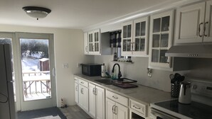 A kitchen with white cabinets, a microwave, a sink, and a stove. - Cozy County Home (Richfield Springs)