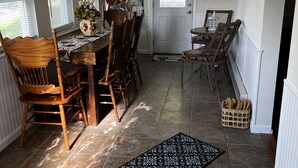 A dining area with a table and chairs, a door, and a window with blinds. - Cozy County Home (Richfield Springs)