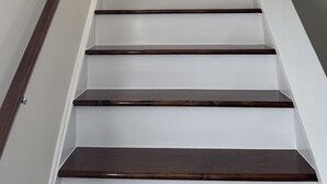 A staircase with white walls and dark wooden steps leading to a landing. - Cozy County Home (Richfield Springs)