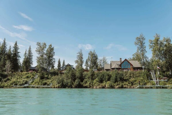 A lakeside property with multiple cabins, surrounded by dense forest and clear blue water.