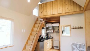 Una cocina compacta con gabinetes de madera, estufa integrada y un refrigerador pequeño.
