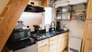 Una cocina compacta con microondas, pileta y muebles de madera.