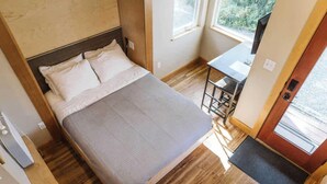Un dormitorio con una cama, un escritorio y una ventana.