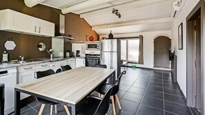 A modern kitchen with white cabinets, a wooden dining table, and black chairs.