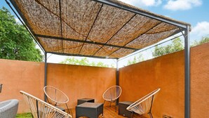 An outdoor patio with wicker furniture, a wooden deck, and a thatched roof.