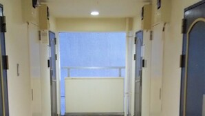 A long, narrow hallway with doors on both sides, leading to a room with a window at the end. - Urban Times Hiroshima (Hiroshima)
