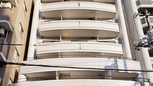 A multi-story building with a tiled facade, multiple balconies, and a sign indicating it houses the Urban Times Hiroshima office. - Urban Times Hiroshima (Hiroshima)