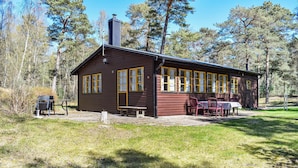 Une cabane en bois avec un coin repas, entourée d’arbres.