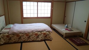 A traditional Japanese room with tatami flooring, a bed with floral bedding, a small table with a book and a cup, and a sliding door. - Houtouji Temple (Yoshino)