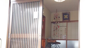 A traditional Japanese entrance with a sliding door, a stone lantern, and a room with tatami mats and a hanging ornament. - Houtouji Temple (Yoshino)