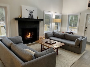 Cozy living room with a fireplace, sofa, and artwork above, offering a warm and inviting atmosphere.