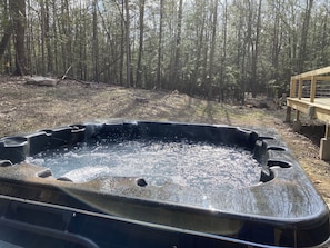 Relax in a serene hot tub surrounded by a peaceful forest setting.