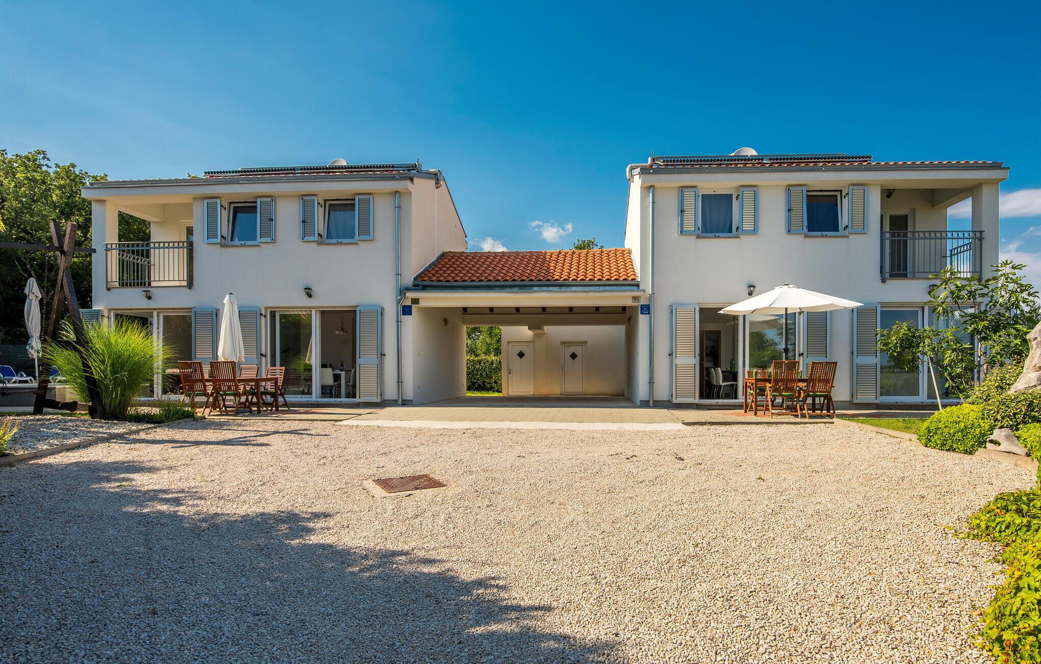 A two-story building with a covered entrance, outdoor seating, and a gravel driveway.