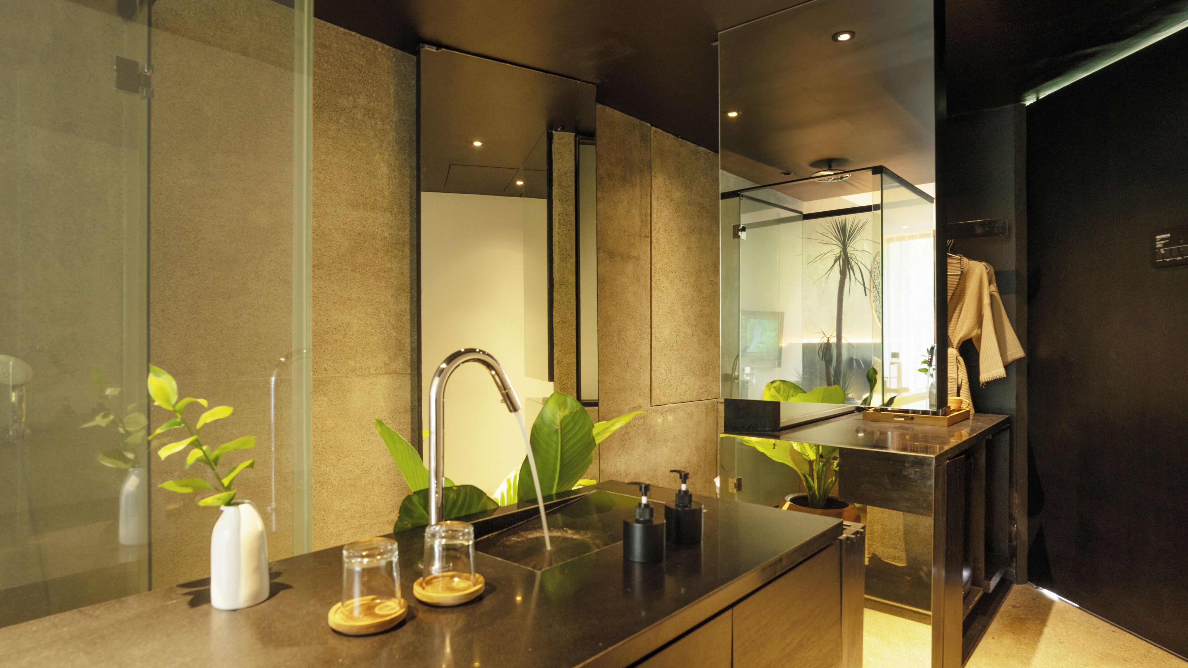 A modern bathroom with a large mirror, a glass shower enclosure, and a wooden vanity with a sink and two soap dispensers.