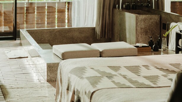 Une chambre d’hôtel moderne dotée d’un grand lit, d’un coin salon, d’une petite table et offrant une vue sur la verdure environnante.