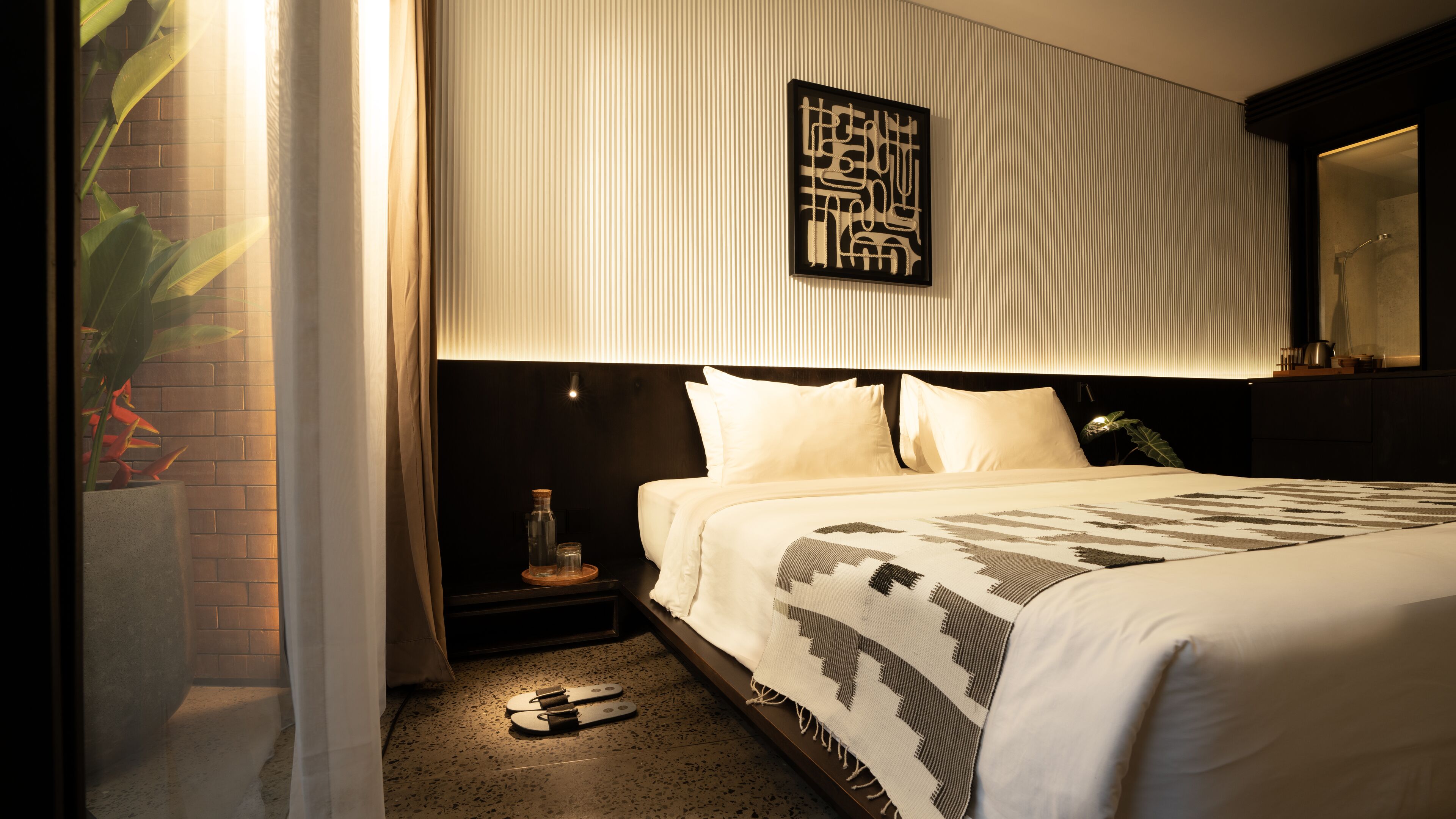 Una habitación de hotel con una cama, una mesita de noche y una obra de arte colgada en la pared.