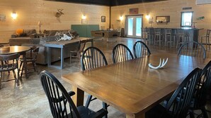 A rustic interior with a wooden dining table, chairs, a pool table, and a bar area.