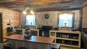 A rustic kitchen with a wooden island, stone walls, and a hanging light fixture.