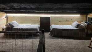 A cozy attic bedroom with two beds, a wooden ceiling, and a skylight.