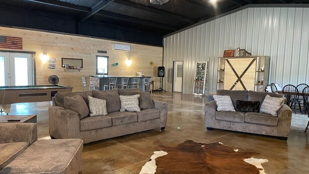 A spacious living area with two sofas, a pool table, and a large cowhide rug.