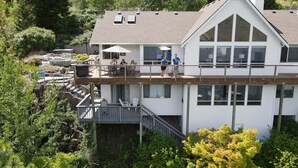 A two-story building with a balcony, outdoor seating, and a view of surrounding greenery.