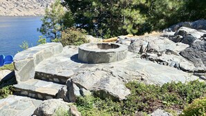 A stone structure with steps leading to a circular stone platform, surrounded by rocks and vegetation.