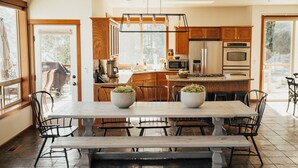 A spacious kitchen with wooden cabinets, a large island, and a dining area with a bench and chairs.