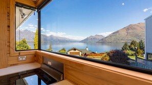 A kitchen with a large window overlooking a lake and mountains.