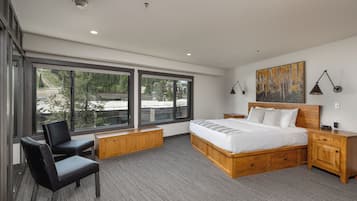 A modern bedroom with a large bed, a desk, a chair, and a painting on the wall.
