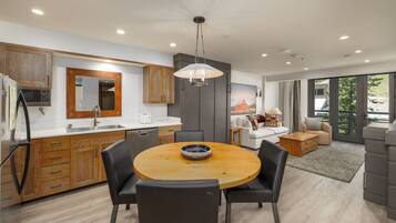 A modern kitchen with wooden cabinets, a round dining table, and a large window.