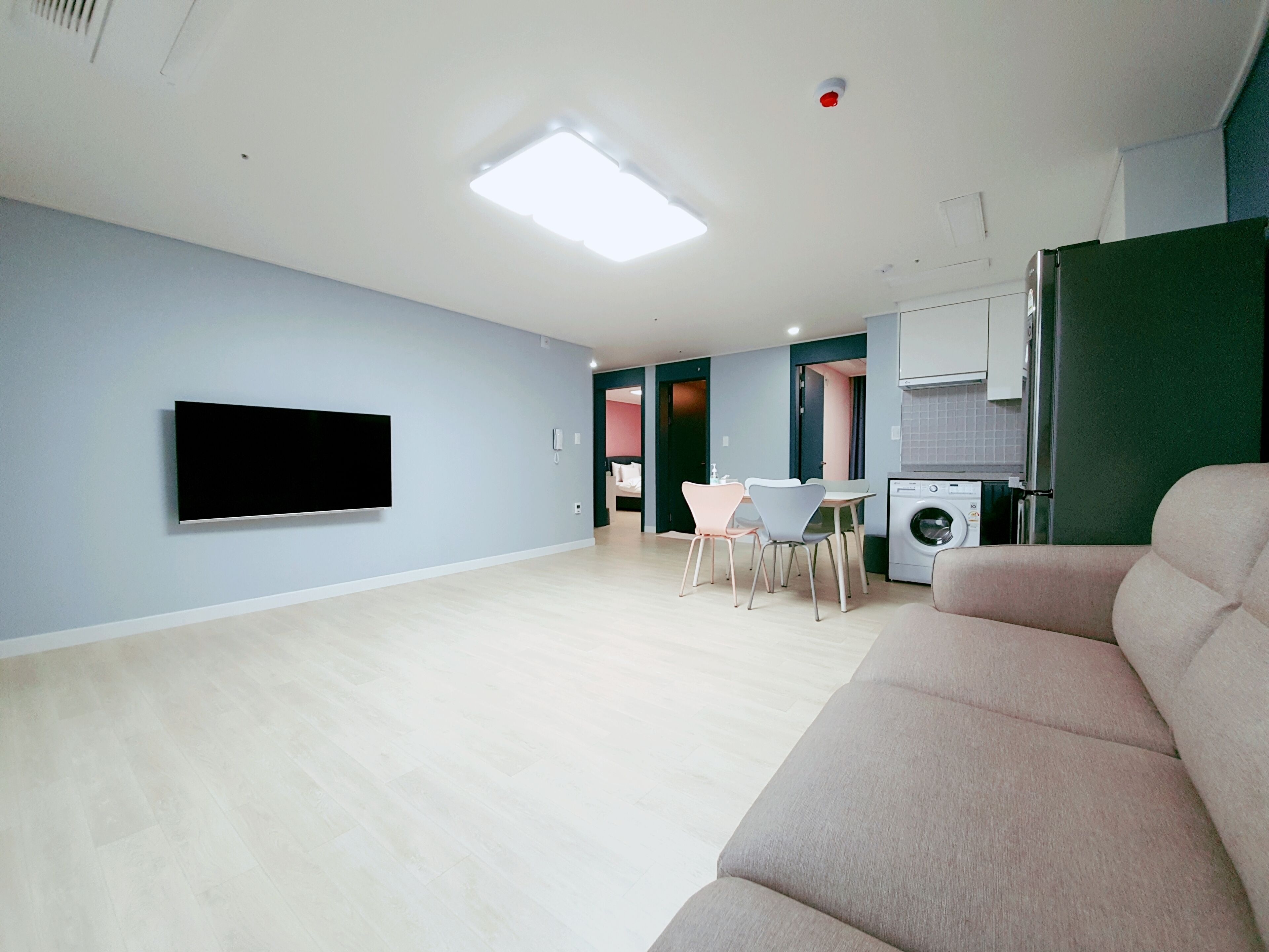 Un salon moderne doté d’un téléviseur à écran plat, d’un canapé, d’un coin repas avec des chaises et d’un lave-linge.