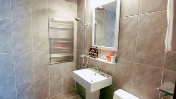 Un baño moderno con ducha, lavamanos e inodoro.
