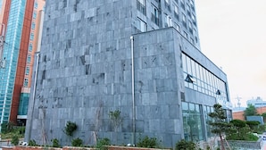 A modern hotel with a textured facade and a prominent sign.