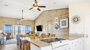 A spacious kitchen with a large island, wooden accents, and a view to the outside. - Beachfront Retreat | Screened Porch | West Beach (Gulf Shores)