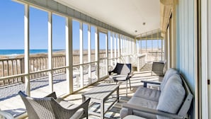 A covered outdoor seating area with a view of the beach and ocean. - Beachfront Retreat | Screened Porch | West Beach (Gulf Shores)
