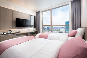 Une chambre d’hôtel avec deux lits, une télévision, un bureau et une vue sur la ville.