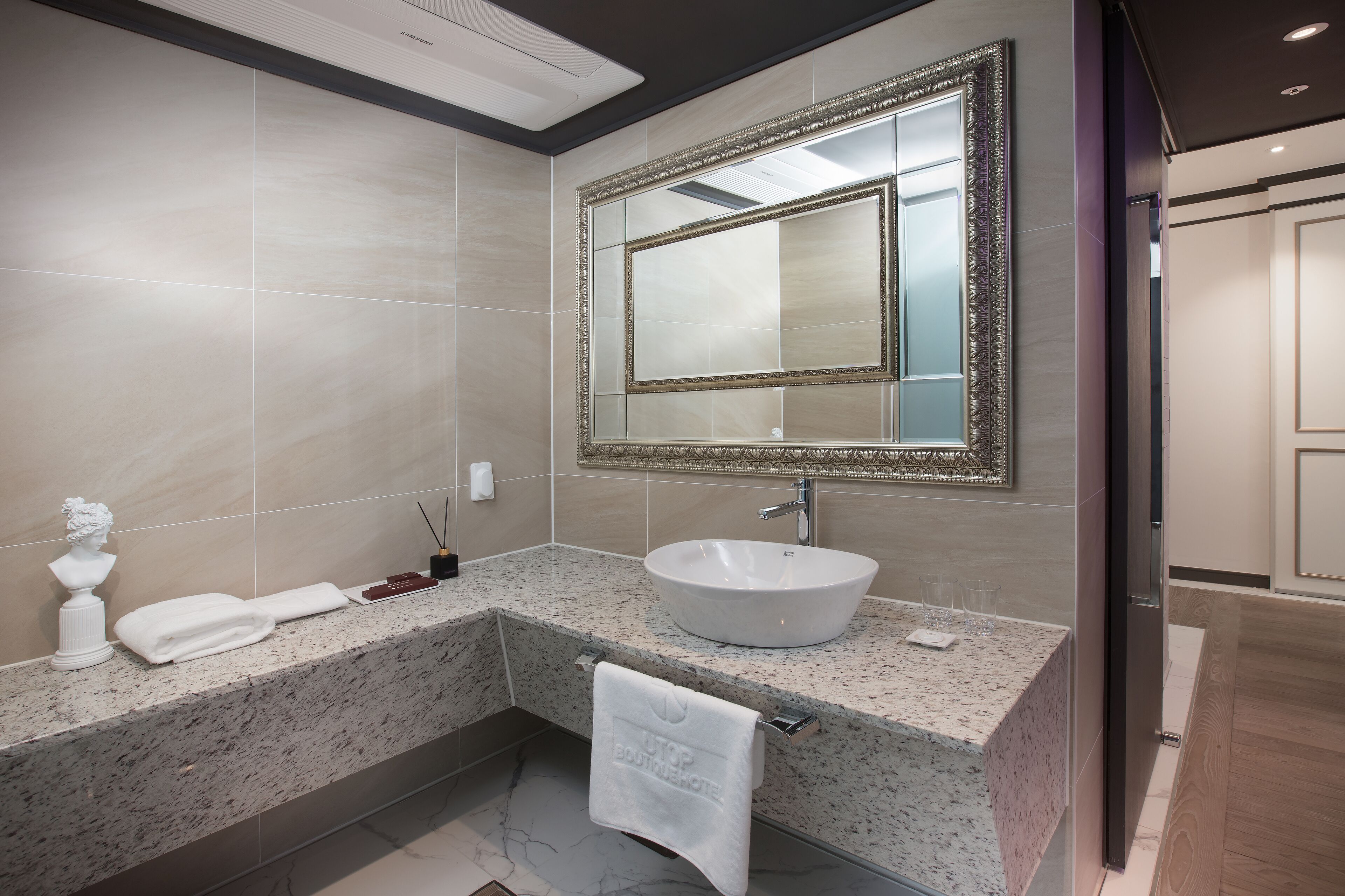 A modern bathroom with a large mirror, a white sink, and a marble countertop.